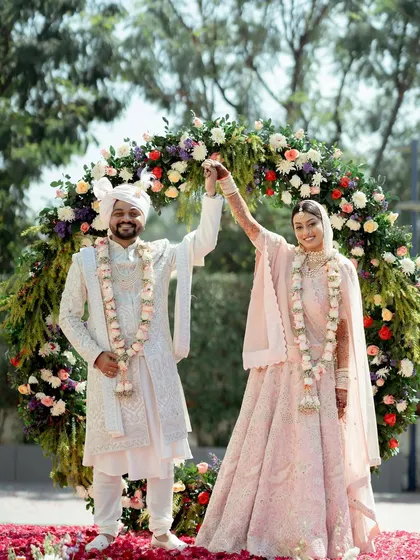 The couple shares a moment of triumph and joy after their wedding ceremony, standing under a beautiful floral arch. This photo perfectly captures the feeling of "we did it!".