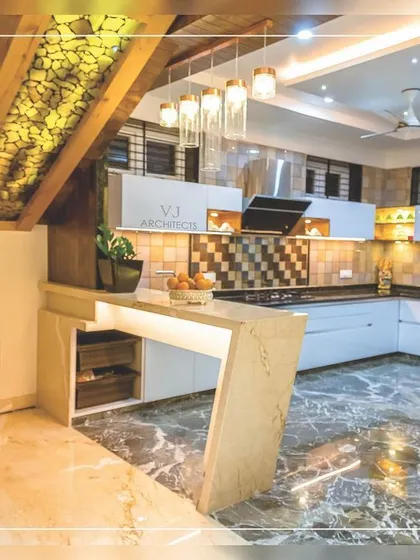 This open kitchen is cleverly integrated under a staircase. It features a breakfast counter, modern appliances, and a mix of marble and tile finishes, proving that any space can be made functional and stylish.