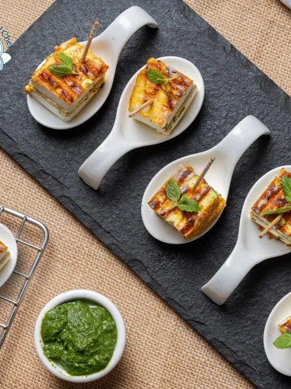 Our Rozali Stuffed Paneer Sandwiches are layered with flavorful chutney and grilled, then served in elegant single-bite portions.