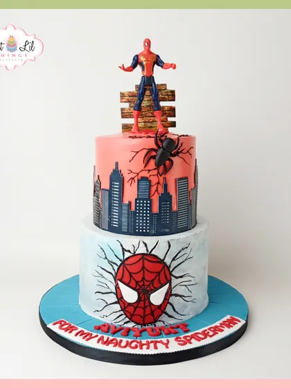 A superhero cake for a "naughty Spiderman." This two-tiered design features a city skyline, a Spiderman mask, and the hero himself perched on top, ready for action.