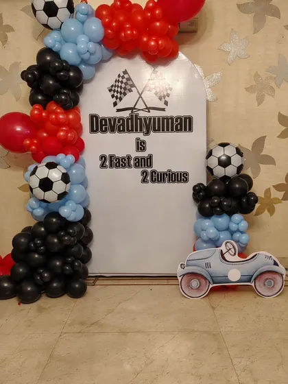 A "2 Fast and 2 Curious" car-themed setup for a second birthday, featuring a custom backdrop and a car cutout.