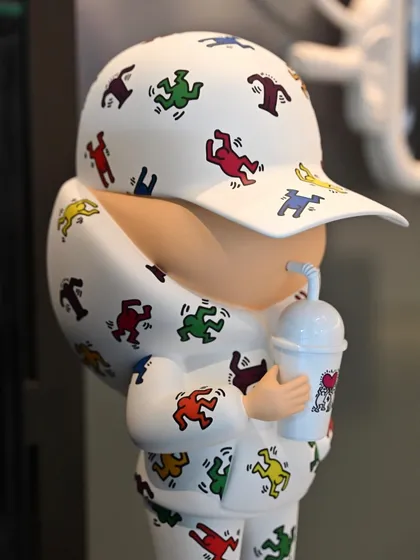 A close-up of the "Kid Cup" sculpture, focusing on the character sipping from its cup, an image of cool nonchalance.