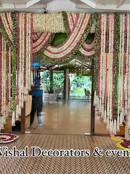 Our team member putting the final touches on a grand floral entrance made of tuberose and marigold garlands for a traditional wedding.