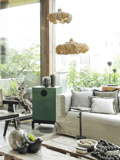 Another view of the sun-filled conservatory, highlighting the green lacquer chesters and an Oorjaa paper-pulp light installation. The design embraces natural materials and the beauty of imperfection.