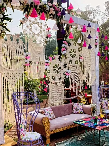 We design vibrant and stylish decor for traditional events, like this outdoor Mehendi seating area featuring a beautiful macrame backdrop, colorful tassels, and eclectic furniture.