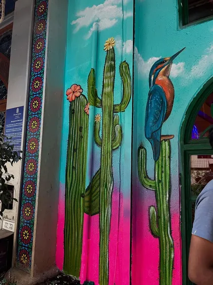 Detailed painting of cacti and a kingfisher on a section of the restaurant's exterior wall.