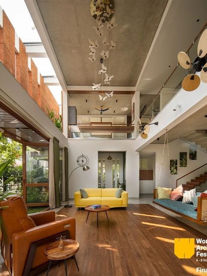 The double-height living room is filled with light from a clerestory window, highlighting the spaciousness and connection to the outdoors.