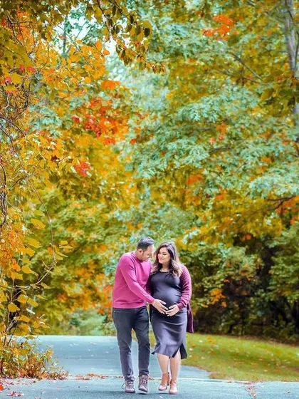 A couple expecting their second child takes a romantic walk down a path lined with fall colors. This shot represents their journey together as their family grows.