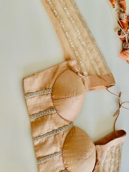 A top-down view of a structured corset blouse in a subtle champagne raw silk. The clean lines are accented with delicate beadwork, offering a contemporary and chic option for the modern bride.