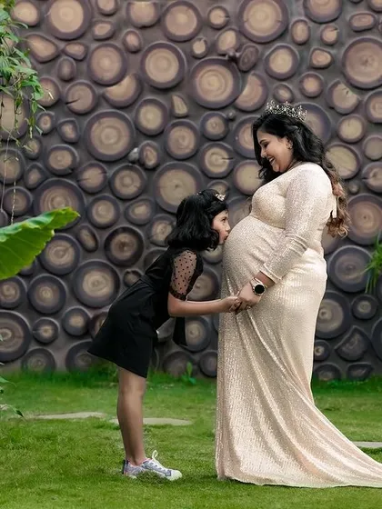 A big sister whispers secrets to her sibling on the way. This outdoor maternity photo captures the beautiful bond between a mother, her daughter, and the new life they are waiting for.