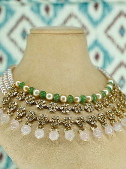 Graceful and extraordinary. This layered necklace combines luminous pearls, green emerald beads, and pastel drops, all accentuated by intricate polki flowers for a delicate, celebratory piece.