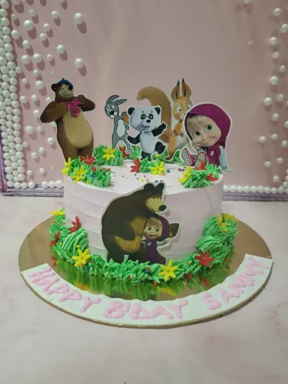 A delightful "Masha and the Bear" themed cake. It features the beloved characters in a forest setting made of green buttercream and edible decorations.