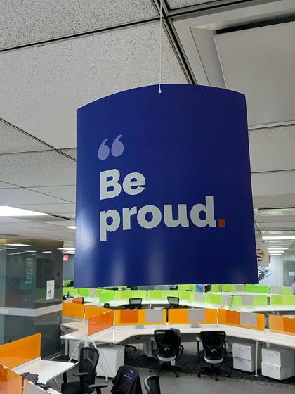 A "Be proud" banner hanging in our office during Pride Month. We believe in creating a space where everyone feels proud of who they are.