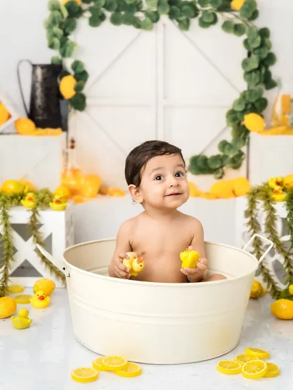 Playing with the rubber ducks in a lemon-themed bath. It’s a perfect, sunny setup to celebrate a one-year-old.