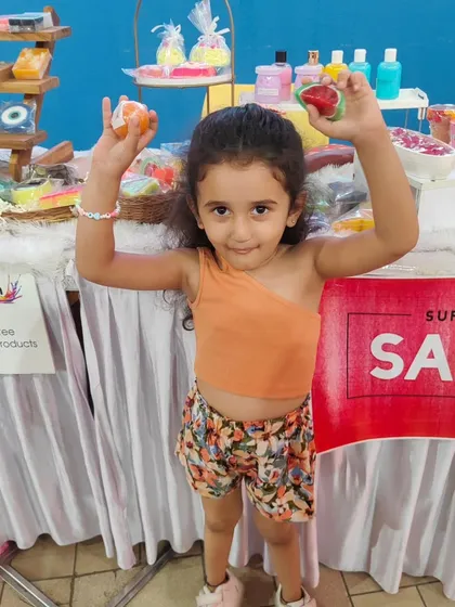 A happy little customer holding up her favorite fruit-shaped soaps at my exhibition stall. Seeing smiles like this is the best part of my job.