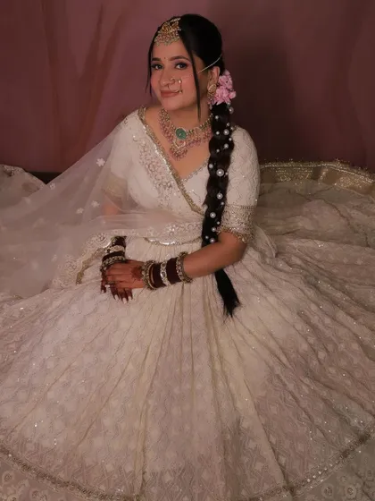 An elegant pose in our white designer lehenga. The pearl-adorned braid complements the outfit's intricate work.