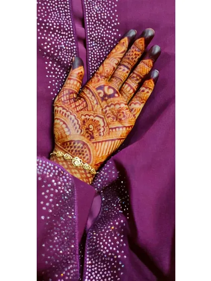 The rich, warm tone of this henna stain looks beautiful against the purple fabric. This design combines traditional motifs for a full and festive look.