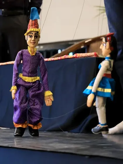 A demonstration of string puppetry during a conference at our Dhaatu International Puppet Festival. An artist skillfully operates two puppets, illustrating the mechanics and grace of this traditional art form.