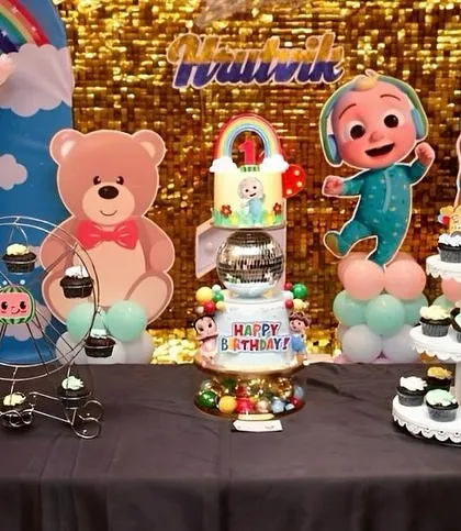 A wide shot of the Cocomelon dessert table, showing the main cake, cupcakes on a ferris wheel, and a cupcake stand.