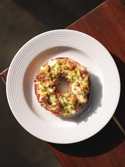 The Jalapeño and Caramelized Onions Pizza Bagel offers a perfect balance of spicy and sweet flavors on a chewy, house-made bagel.