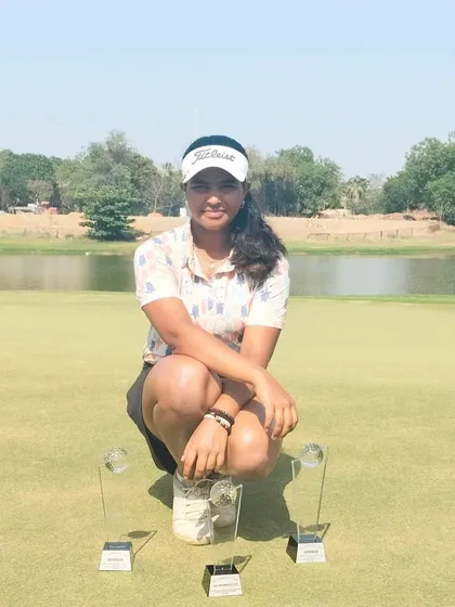 Rashi Mishra on the green with her trophies from the Kalhaar Greens tournament, a testament to her dominant performance.