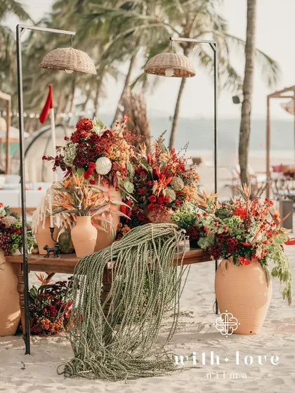 A stunning installation of tropical fruits and flowers on the beach, with rattan lamps adding to the rustic, seaside vibe.