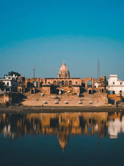 The reflection of Bhramhavart Ghat in Bithoor on the calm river waters, creating a perfectly symmetrical and peaceful image.