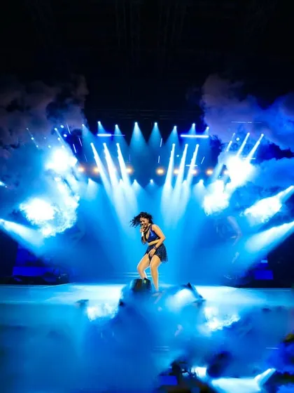A stage drenched in blue light and smoke. We use professional lighting and atmospheric effects like pyros and smoke to build drama and match the energy of every song.