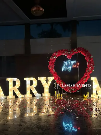 The perfect proposal setup with "Marry Me" marquee letters and a neon "Will you marry me?" sign.
