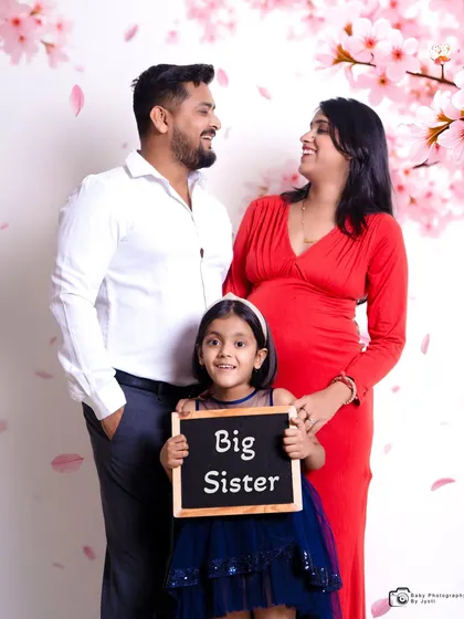 A joyful family maternity announcement in my Gurgaon studio. Including older siblings with fun props like this 'Big Sister' sign makes for a memorable and inclusive family photoshoot.