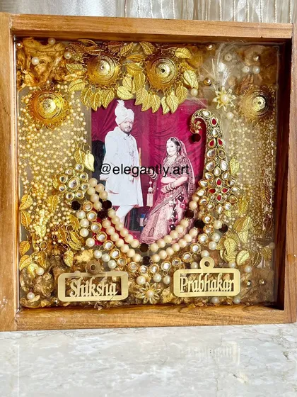 A full view of the magnificent 16x16 inch teakwood frame, preserving a couple's varmala, kalgi, and other wedding ornaments. This piece is a grand celebration of their special day.