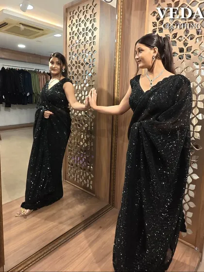 A happy client admiring her look in this stunning black sequin rental saree.