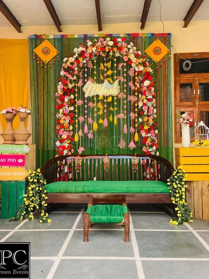 A classic and rustic Mehndi setup for a home function. I used a wooden swing (jhoola) with a green cushion, a floral arch, and a 'Mehndi' neon sign to create a cozy and traditional vibe.