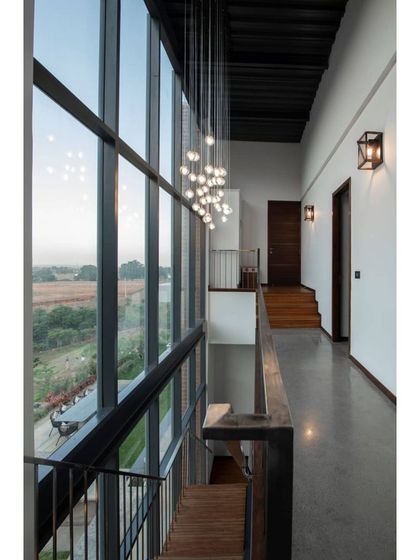 A view from the upper-level corridor, looking down into the main living area. The cascading chandelier adds a touch of elegance, while the large windows provide an uninterrupted vista of the countryside.