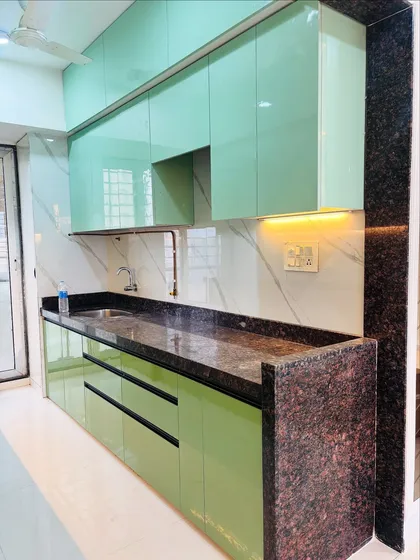 A different angle of the green kitchen, showing the handleless drawers and cabinets that contribute to its clean, minimalist aesthetic.