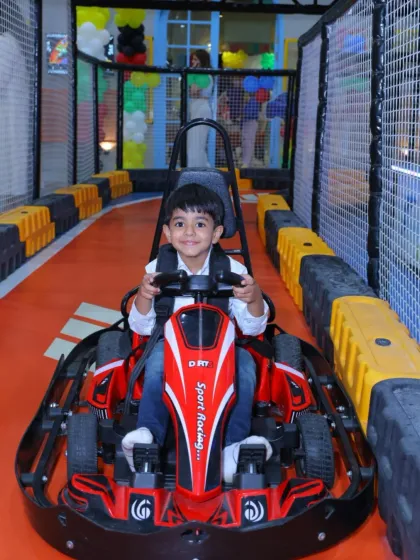 This young man is all smiles as he gets ready to drive his red go-kart. The track awaits!