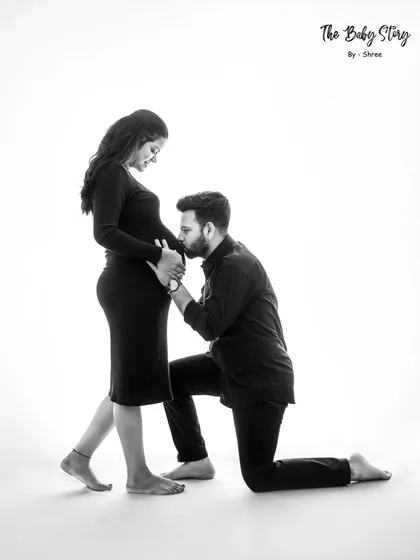 A classic and loving pose where the partner kneels to kiss the baby bump. In black and white, this gesture becomes even more tender and symbolic.