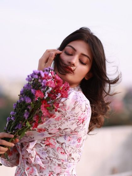 A playful and gentle moment. The way she interacts with the flowers and the soft breeze creates a charming and candid feel.