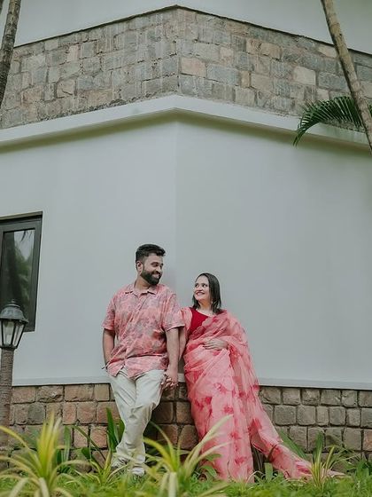 A relaxed portrait against the modern architecture of a resort building, framed by palm trees.