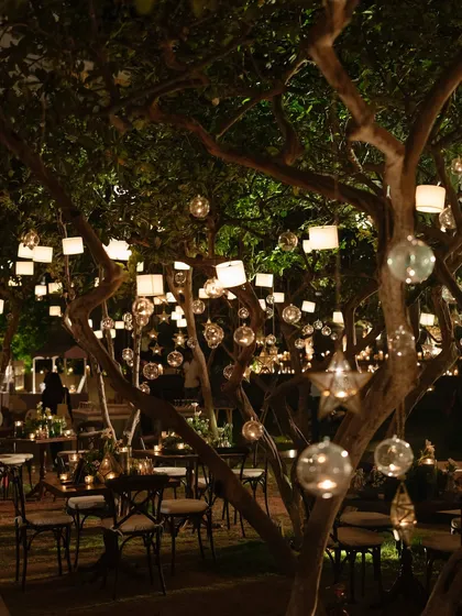 An enchanted forest theme for a welcome dinner, with dozens of glass orbs and lanterns hanging from the trees. This lighting design created a magical, intimate ambiance for an evening of celebration.