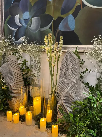 A serene and modern arrangement featuring white tuberoses and baby's breath set against textured stone props and warm candlelight. This type of decor is perfect for creating a calm and sophisticated ambiance.