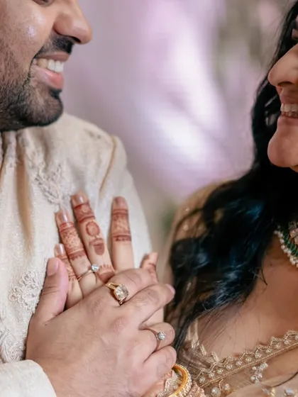 A close-up of the couple's hands and smiling faces after the ring exchange, a perfect symbol of their new commitment.
