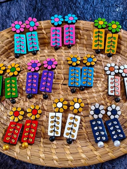 These rectangular dangler earrings have a floral stud and a hand-painted leaf-vine pattern. They are available in a wide array of colors.