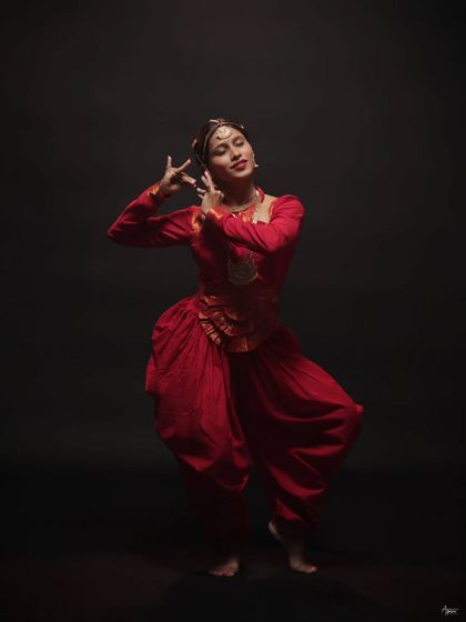 This frame captures the expressive hand gestures, or mudras, that are central to Bharatanatyam. The soft lighting on her face emphasizes her focused and serene expression.