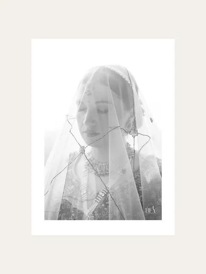 A high-key black and white portrait of a bride under her veil, creating a soft and ethereal look.