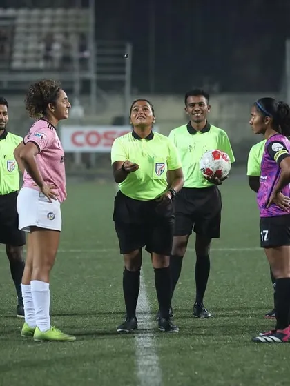 The pre-match coin toss under the floodlights, setting the stage for a night game.