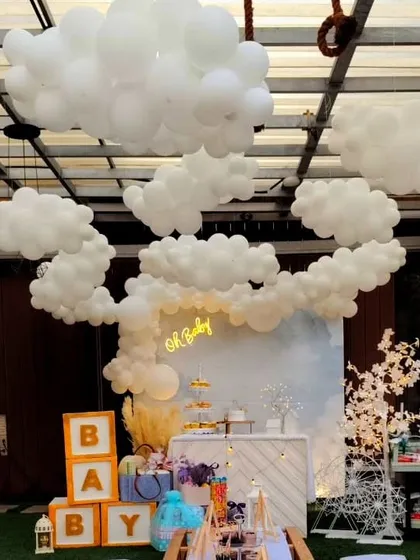 A dreamy "Oh Baby" shower with a celestial, cloud-like atmosphere. I created an installation of white balloons on the ceiling to look like clouds, with a simple backdrop and neon sign below.