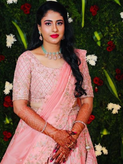 A close-up of the pink lehenga look. You can see the intricate mehndi and the beautiful contrast between the soft pink outfit and the bold red lip.