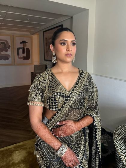 A full-length view of Shanel's stunning black and gold welcome dinner outfit. The sleek high ponytail adds a touch of modern sophistication to her traditional attire.