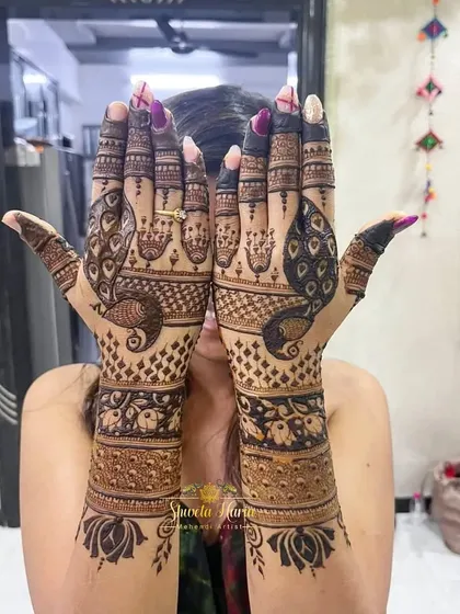 A fancy back-hand design that is perfect for the bride's tribe. It features large, graceful peacocks, elephant motifs, and hanging jhumkas for a festive and royal feel.